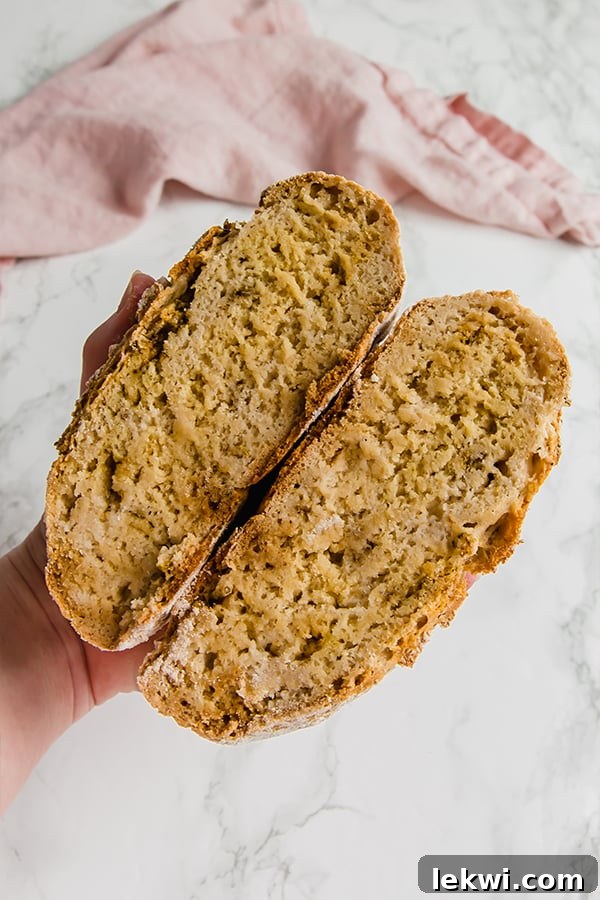 A beautifully rustic No-Knead Gluten-Free Bread loaf, sliced in half to reveal its tender crumb, sitting on a wooden cutting board.