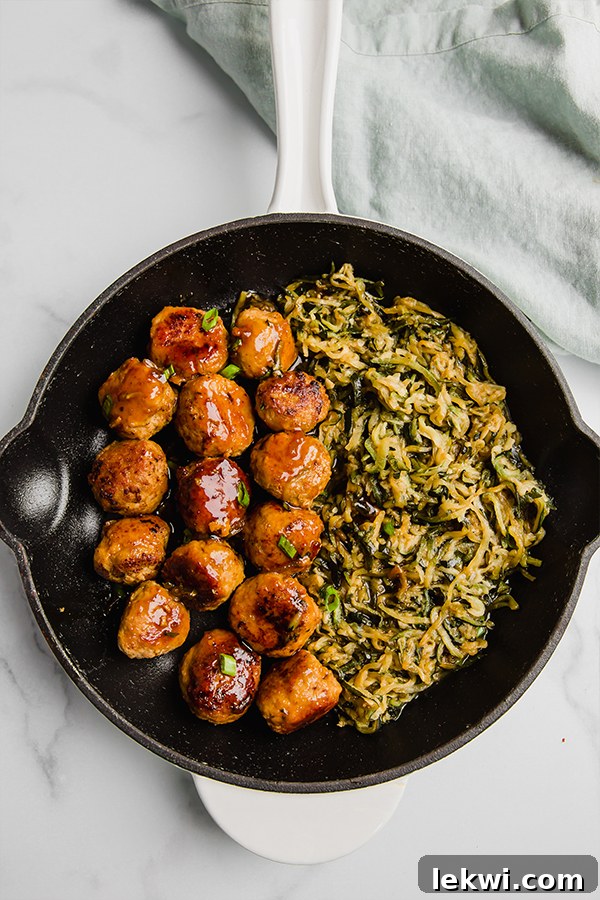 Teriyaki turkey meatballs simmering in a skillet with zucchini noodles, ready to be served.
