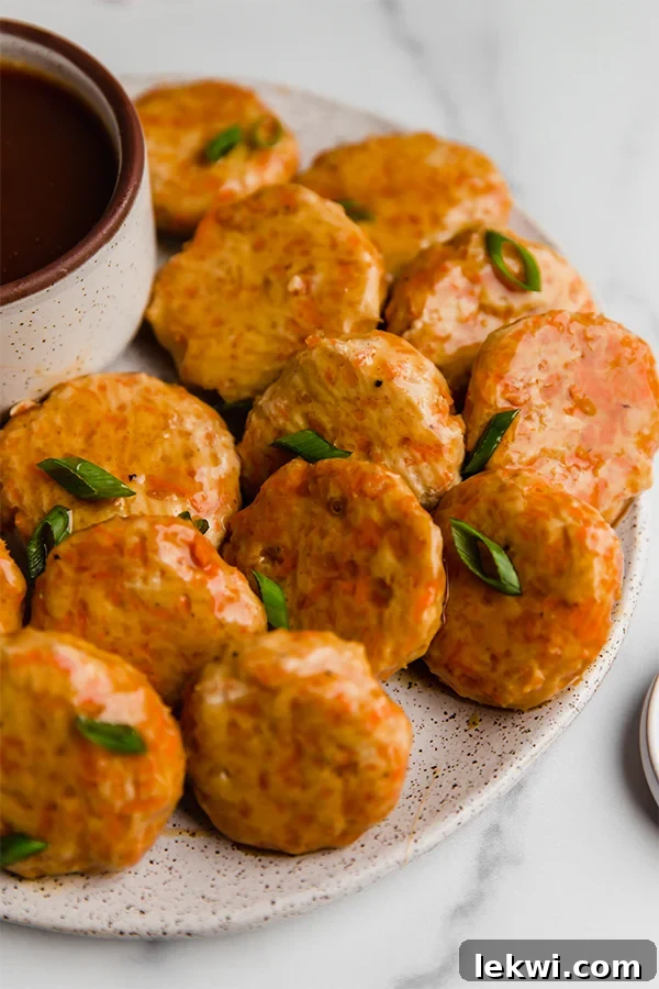 Sweet and sour chicken poppers on a plate with a side of sauce.