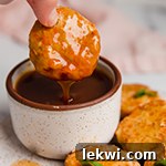 Sweet and sour chicken poppers on a plate with one being dipped in sauce.