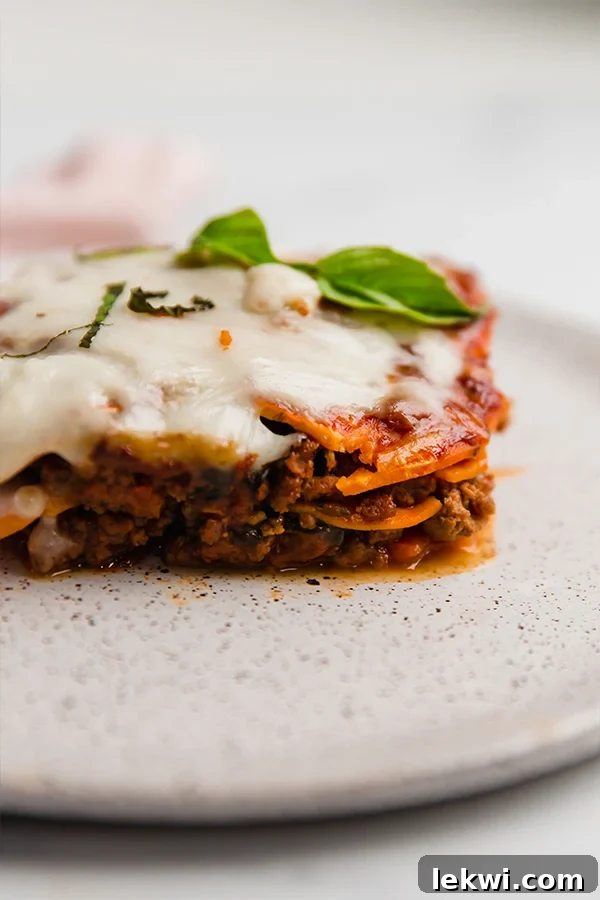 A serving of sweet potato lasagna on a plate, generously topped with fresh basil leaves.