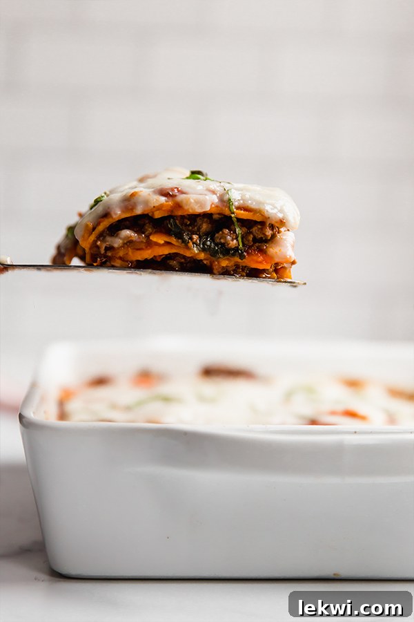 A sweet potato lasagna in a casserole dish, with a slice being removed by a spatula, revealing the delicious layers within.