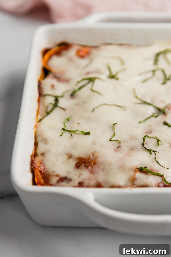 A large baking dish filled with a baked sweet potato lasagna, glistening with its creamy topping, ready to be cut and served.