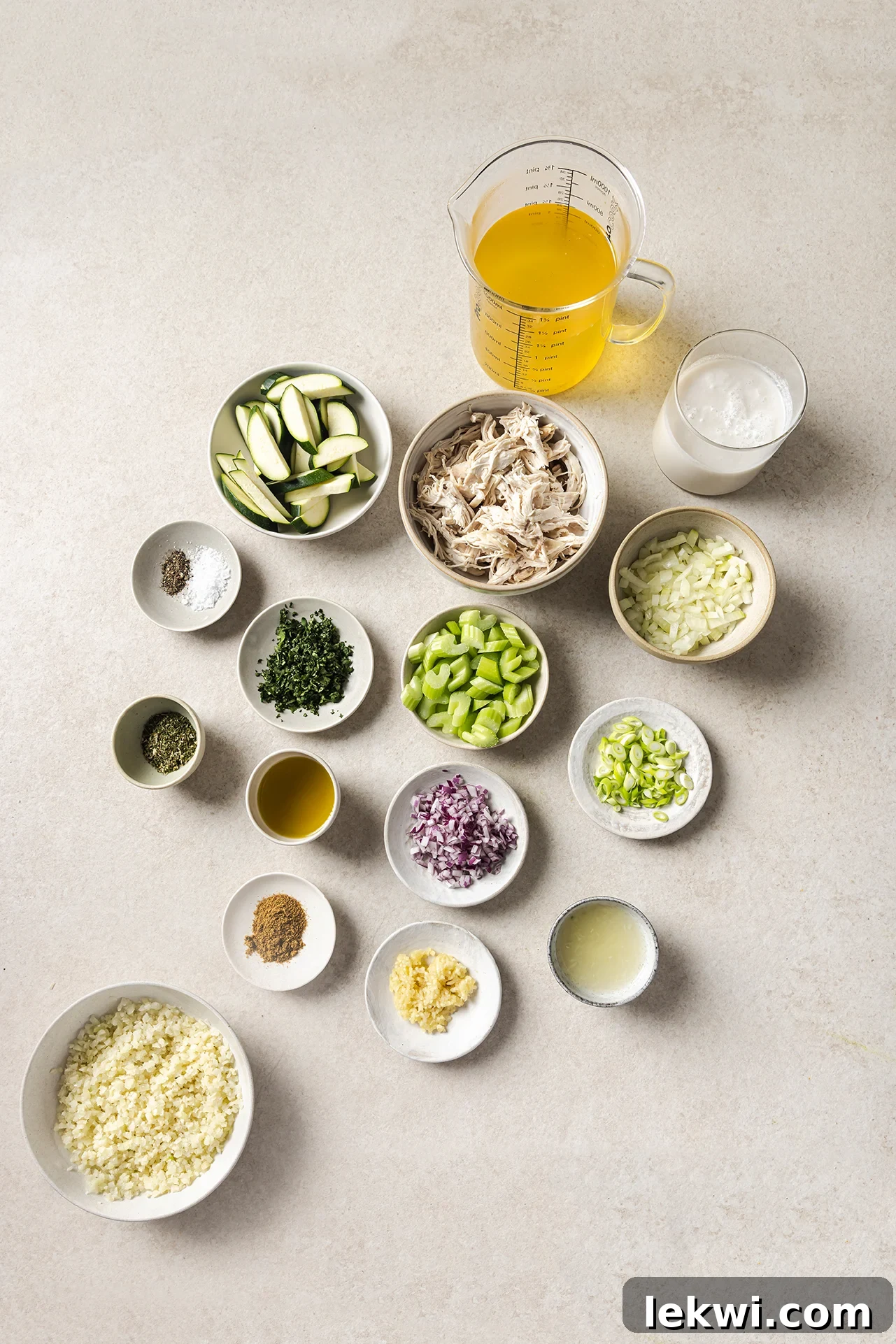 All fresh ingredients neatly arranged in bowls for making white chicken chili, including shredded chicken, various vegetables, and spices.