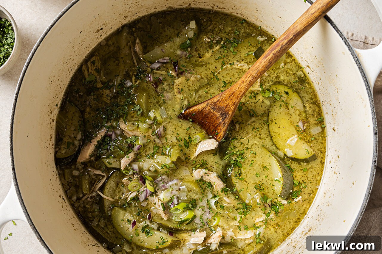 Chicken broth, coconut milk, and spices being added to the sautéed vegetables in a large pot, ready to simmer.