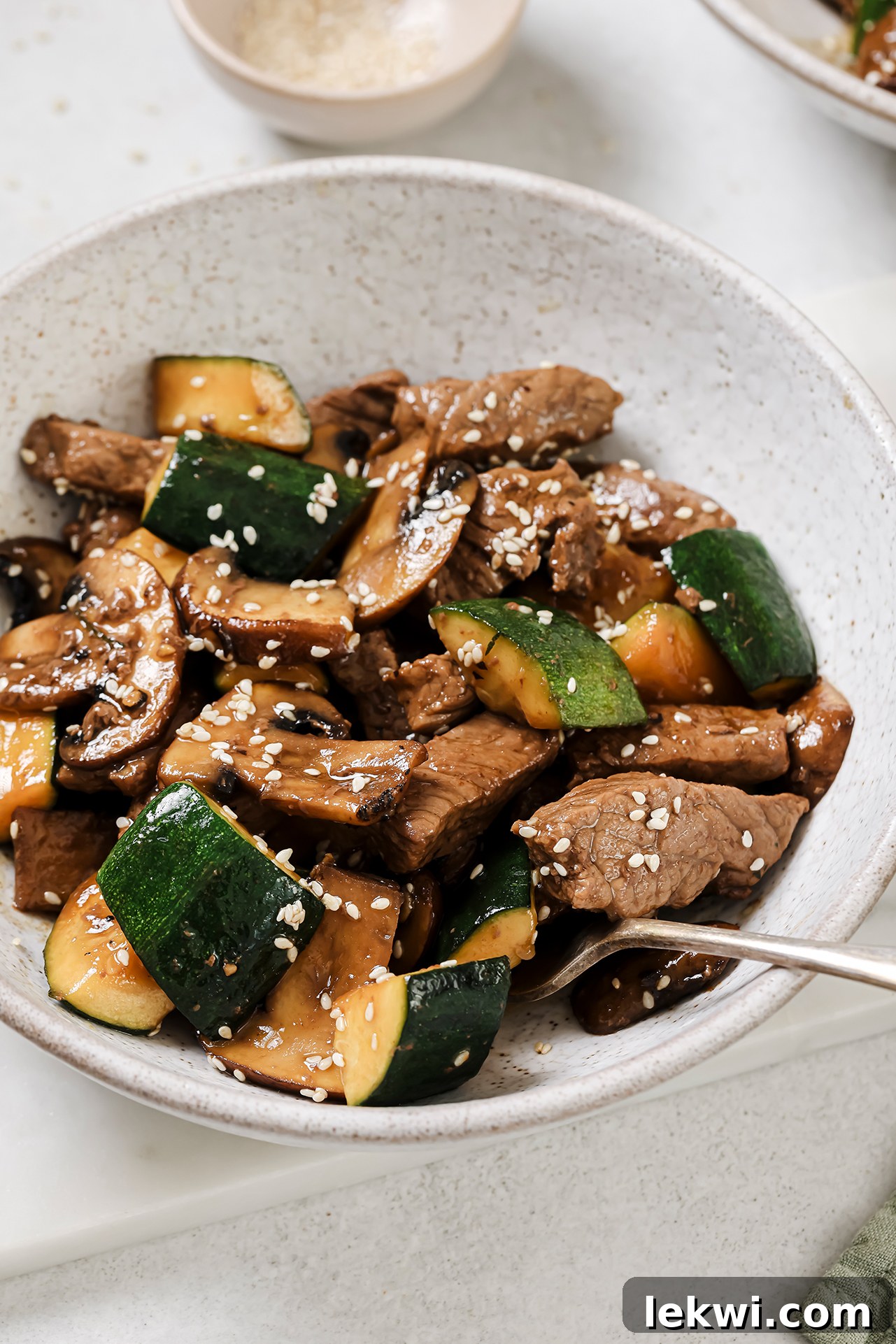 A beautifully presented bowl of hibachi steak bites with zucchini and mushrooms, garnished with sesame seeds and ready to be enjoyed.