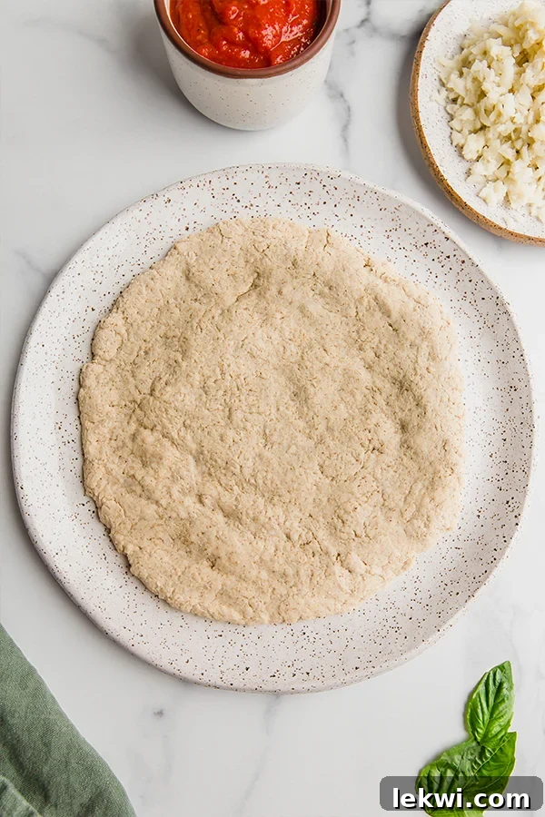 A perfectly golden and crispy AIP pizza crust resting on a white plate, showcasing its texture and readiness for creative toppings.