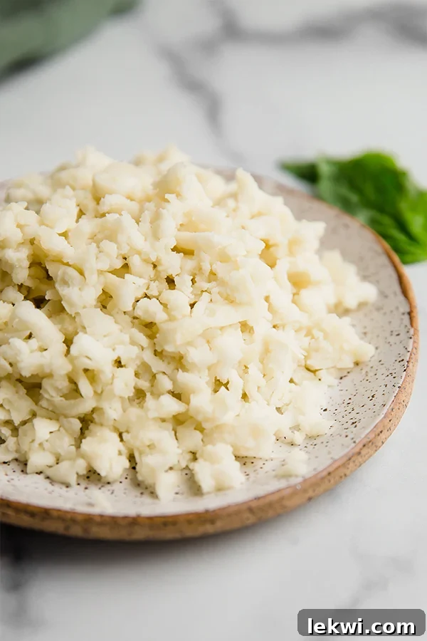 Shredded dairy free cheese on a plate with basil in the background.