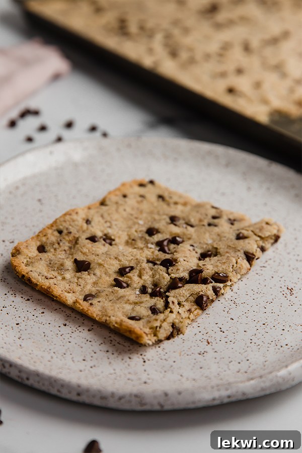 A slice of sheet pan cookie on a speckled plate, ready to be enjoyed.
