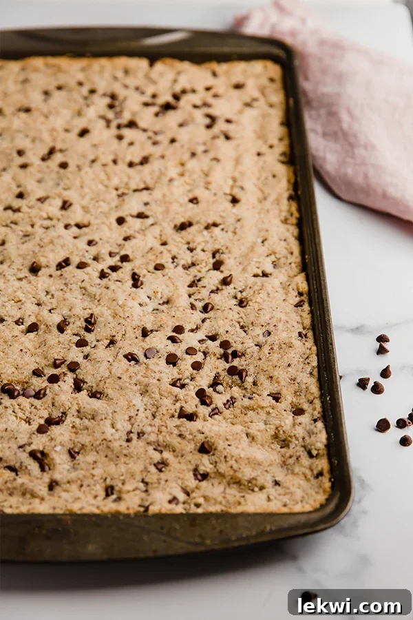 sheet pan chocolate chip cookie on pan with some slices already removed, showing its shareable nature