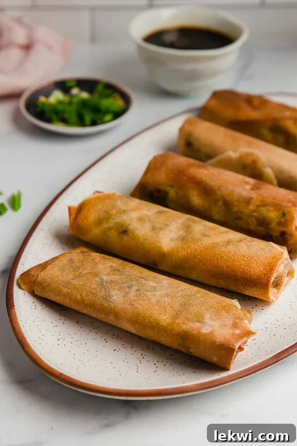 A platter of cooked air fryer egg rolls, golden brown and crispy.