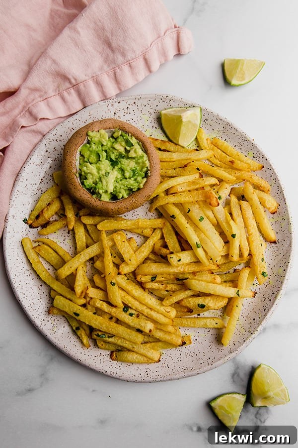 Golden-brown jicama fries served on a white plate with a side of creamy guacamole, ready to be enjoyed.