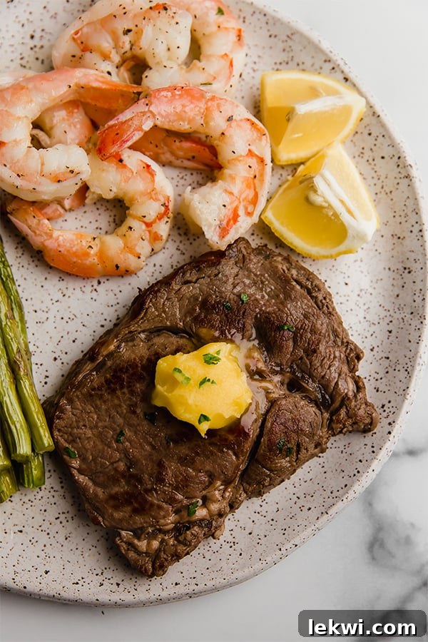 Sizzling ribeye steak and succulent shrimp artfully arranged in a cast-iron skillet, ready to serve.