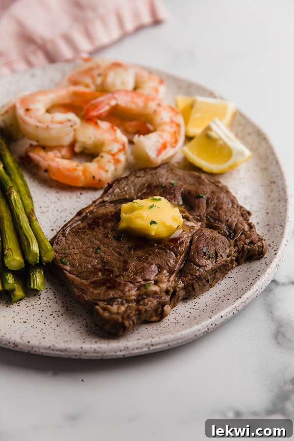 Beautifully plated surf and turf skillet with steak slices, succulent shrimp, and fresh parsley garnish.