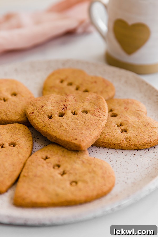 Three perfectly baked conversation heart sugar cookies, paleo and AIP, arranged on a rustic plate.