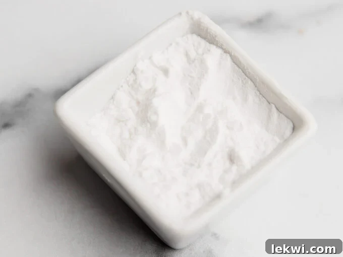 A bowl containing white arrowroot flour, highlighting its use as an egg substitute.