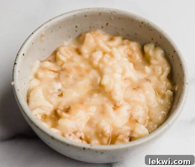 A bowl of freshly mashed ripe banana, indicating its use as a natural egg substitute.