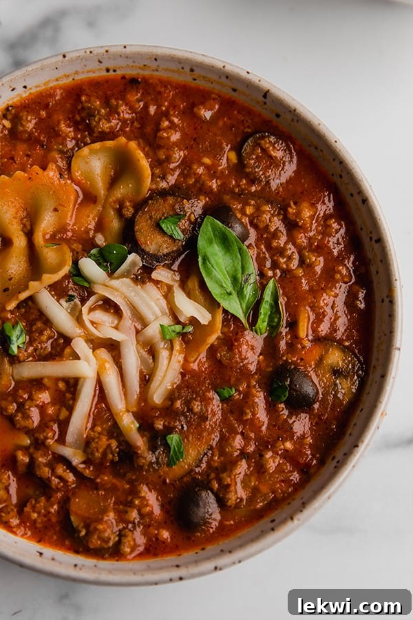 A steaming bowl of gluten-free pizza soup, garnished with fresh herbs, ready to be enjoyed.