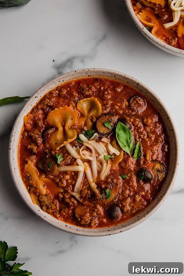A close-up shot of a bowl of gluten-free pizza soup, showcasing the ingredients and rich broth.