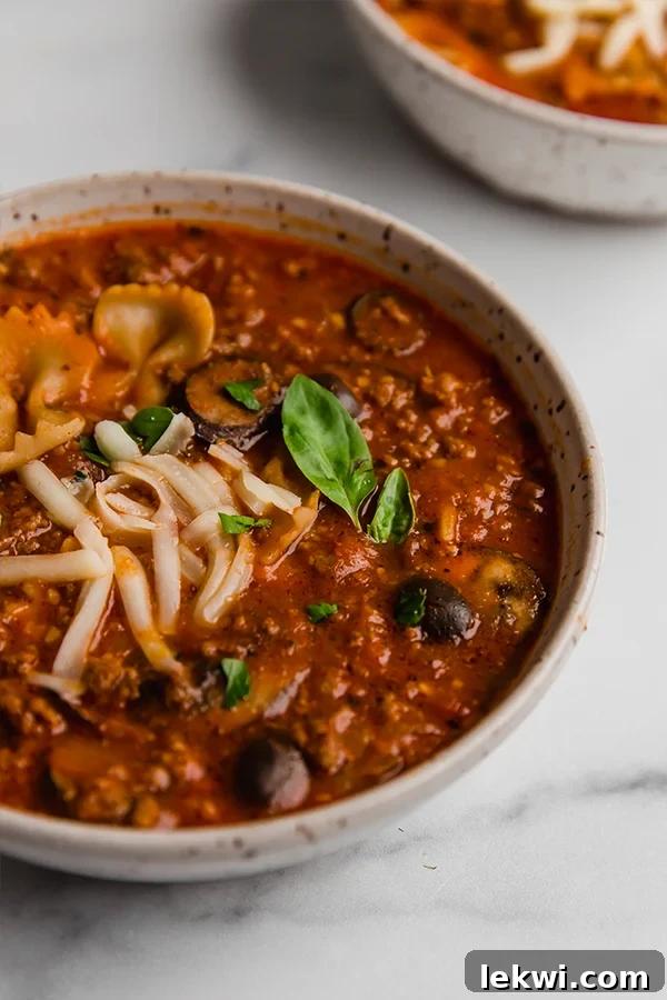 A comforting bowl of gluten-free, paleo, and AIP-friendly pizza soup, garnished with fresh basil.