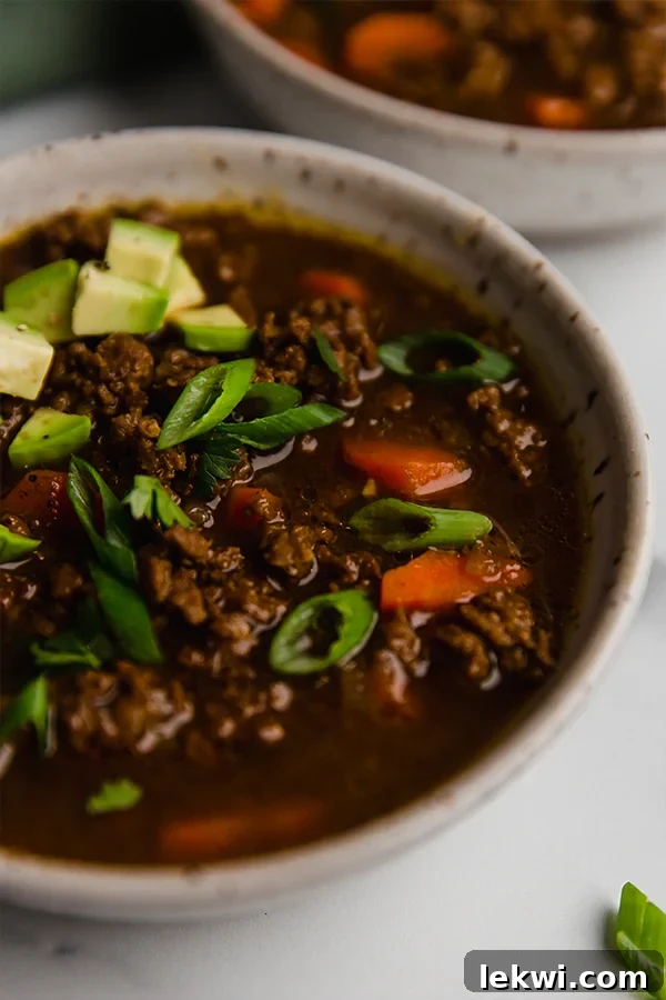 A close-up shot of the Asian Inspired Chili, served in a rustic bowl with vibrant toppings.