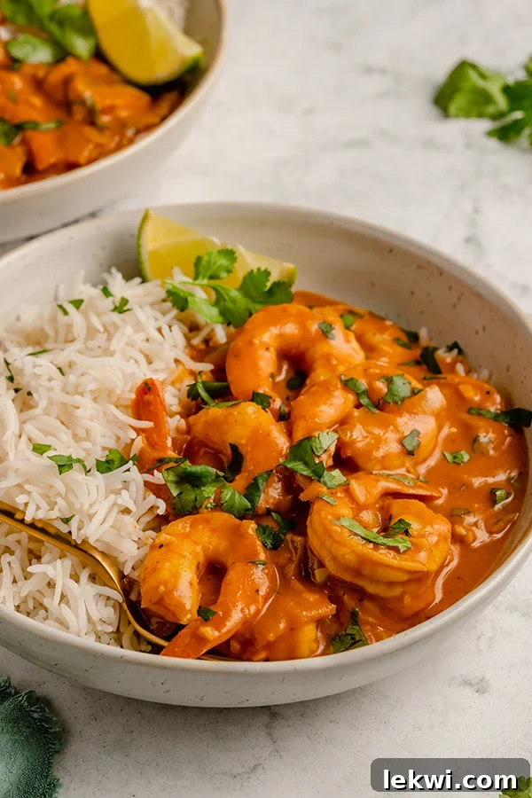 Shrimp curry in a bowl with rice and a fork.
