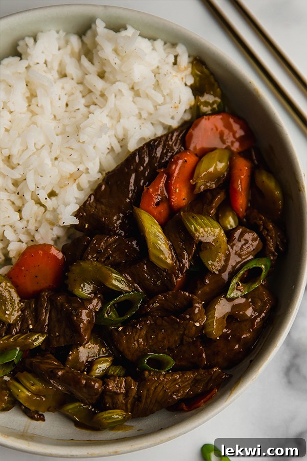 Beef and Celery Stir Fry served with white rice, garnished with green onions