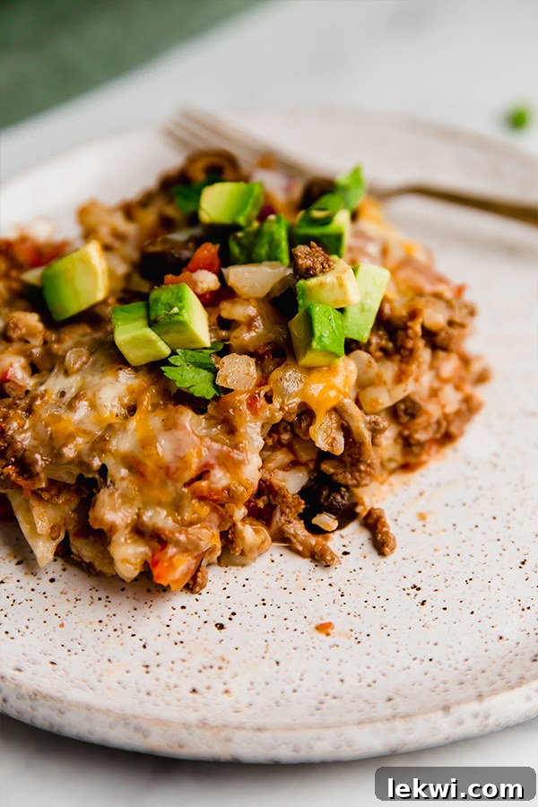 A serving of taco cauliflower rice casserole on a white plate, garnished with fresh cilantro.