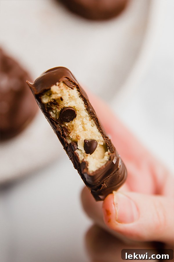 A hand holding a chocolate covered cookie dough Easter egg, showcasing its perfect shape and delicious coating.
