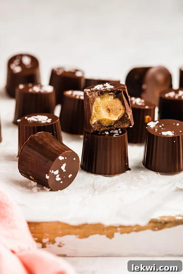 Several homemade salted caramel cups, one showcasing a perfect bite, arranged invitingly on a clean surface.