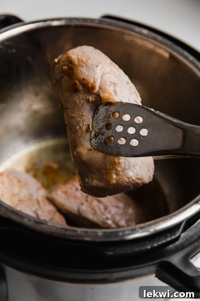 Instant Pot Pork Tenderloin slice held by tongs