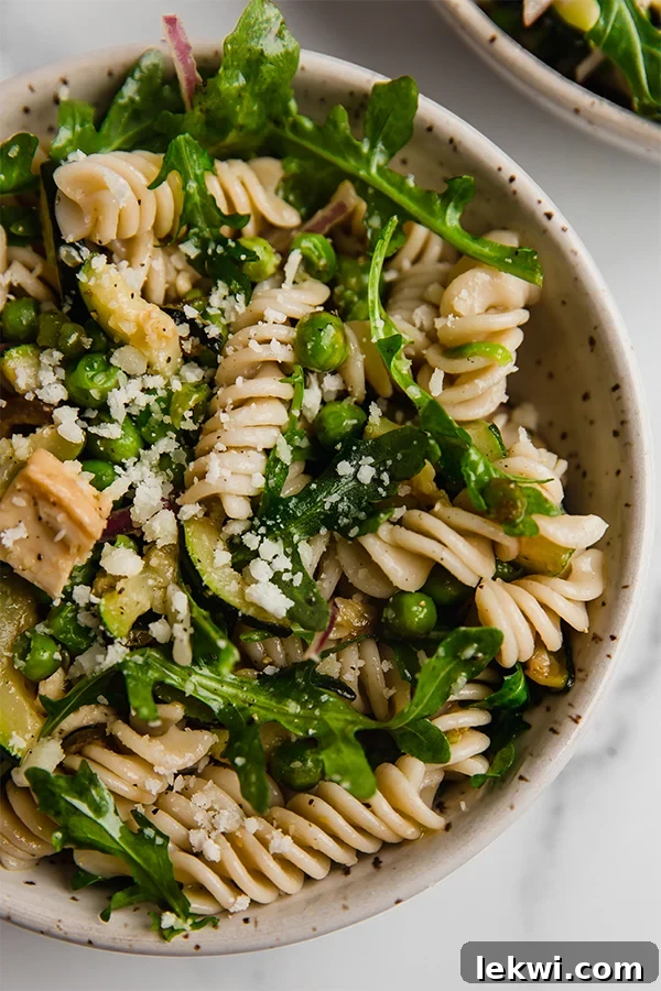 Vibrant Spring Pasta Salad in a bowl, featuring gluten-free pasta, succulent chicken, and fresh green vegetables, topped with a simple, zesty dressing.
