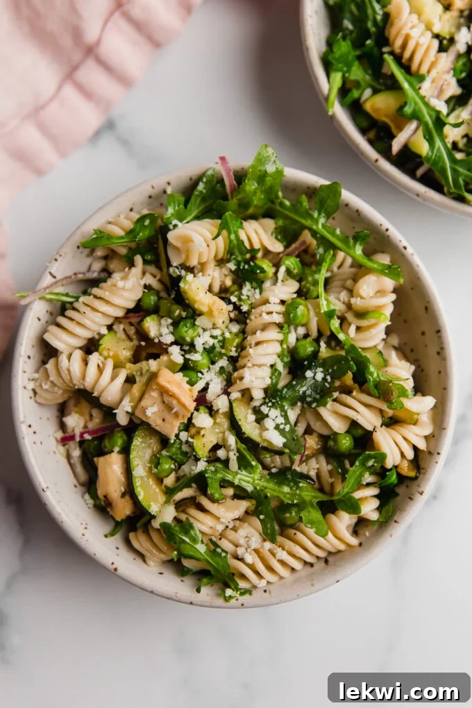 Close-up of a serving of Spring Pasta Salad in a white bowl, showcasing its fresh ingredients and vibrant colors.