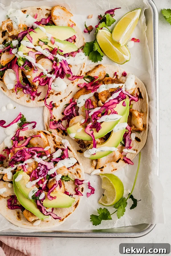 Fish tacos with crisp slaw nestled in a lined baking dish, showcasing a perfectly seared fish fillet.