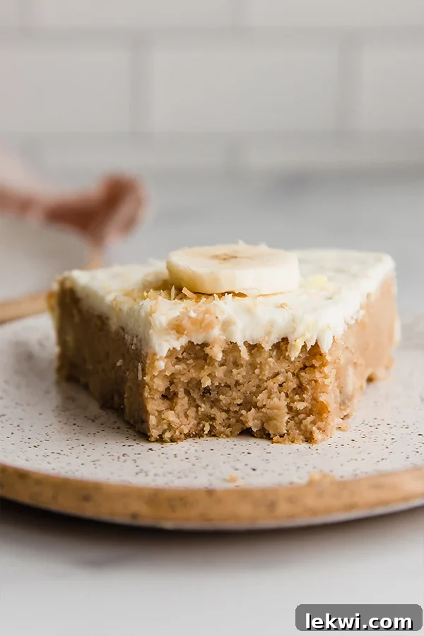 A beautifully frosted slice of coconut flour lemon banana cake with a bite missing, showcasing its moist texture and inviting appeal.