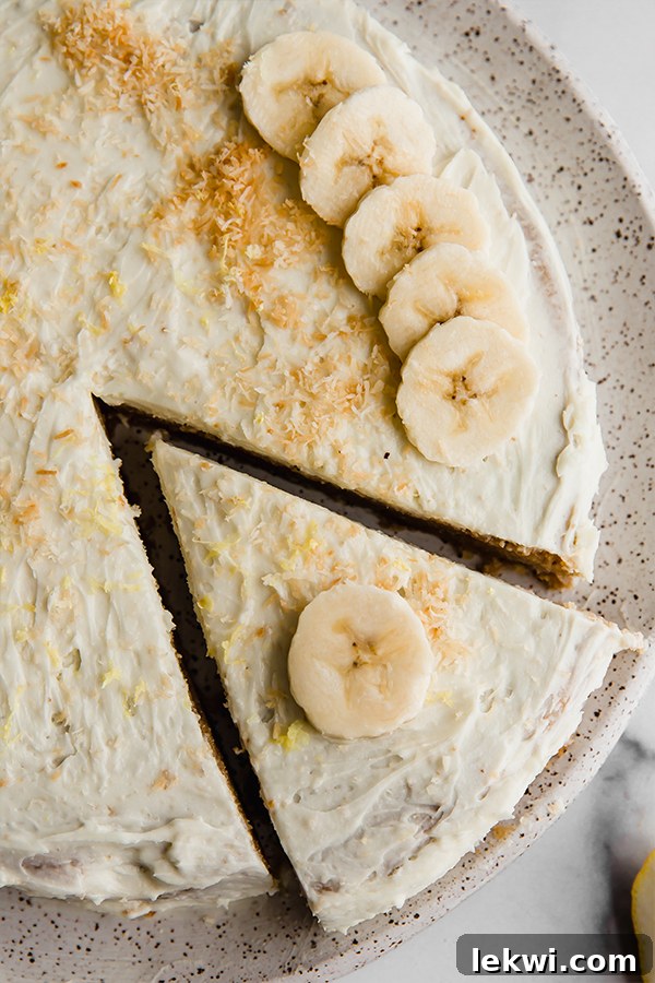 A slice being carefully removed from a whole coconut flour lemon banana cake, revealing its soft interior.