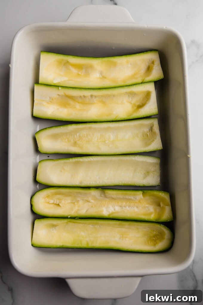 Scooped-out zucchini halves prepared in a baking dish, perfectly ready for their savory stuffing.