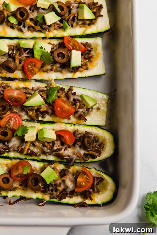 A tantalizing up-close top view of stuffed zucchinis in a baking dish, showcasing the vibrant toppings.