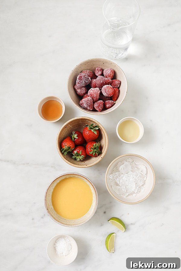 Ingredients for strawberry margarita mocktail laid out, including orange juice, honey, frozen strawberries, limes, and sparkling water.