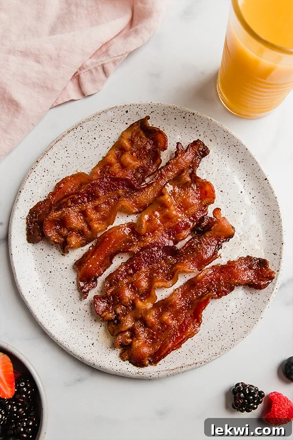 Plate of perfectly cooked oven-baked bacon, golden brown and crispy.