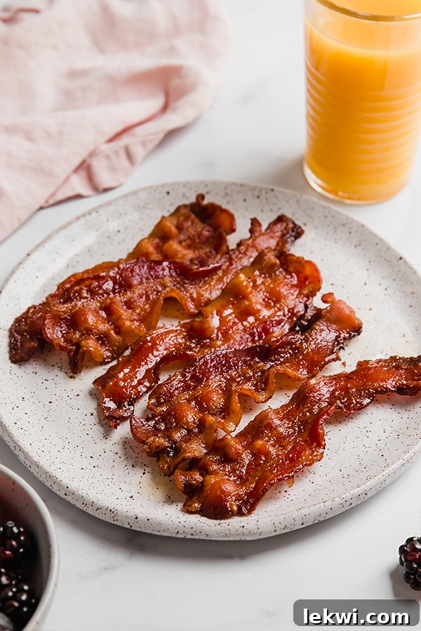 Crispy strips of oven-baked bacon neatly arranged on a white plate.