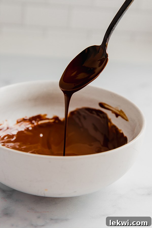 Melted chocolate glaze smoothly dripping from a spoon, illustrating the rich texture for donut topping.