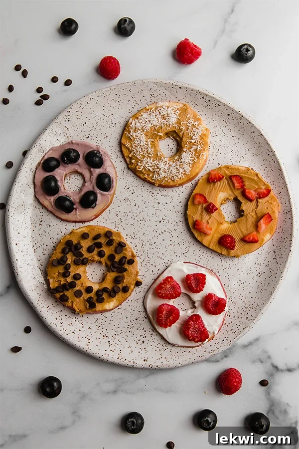 Apple "donuts" with different toppings on a plate.