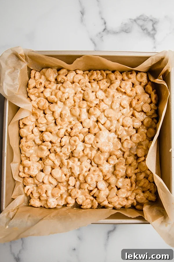 Cereal bars pressed into a square pan, flattened and ready to set in the fridge before cutting.