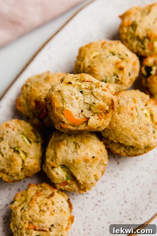A delicious gluten-free veggie muffin with a bite taken out, resting on a clean white plate.