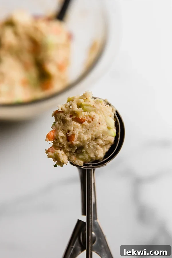 A spoon holding a scoop of the gluten-free veggie muffin mixture, ready for the muffin tin.