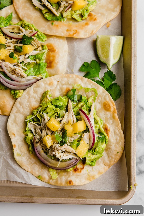 Brightly colored Mango Chicken Tostadas assembled on a baking sheet, ready to be enjoyed.