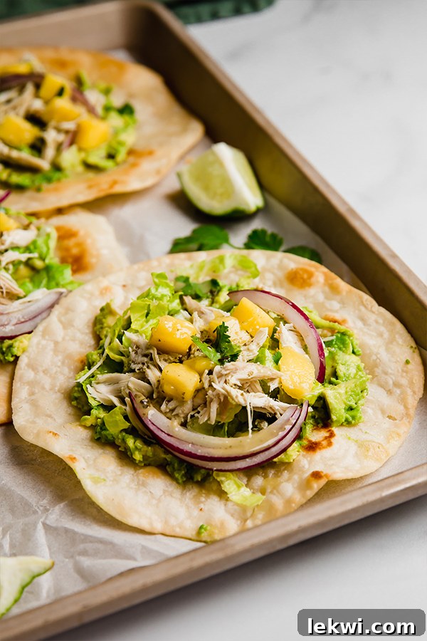 Three beautifully assembled Mango Chicken Tostadas, perfectly garnished and ready to be served.