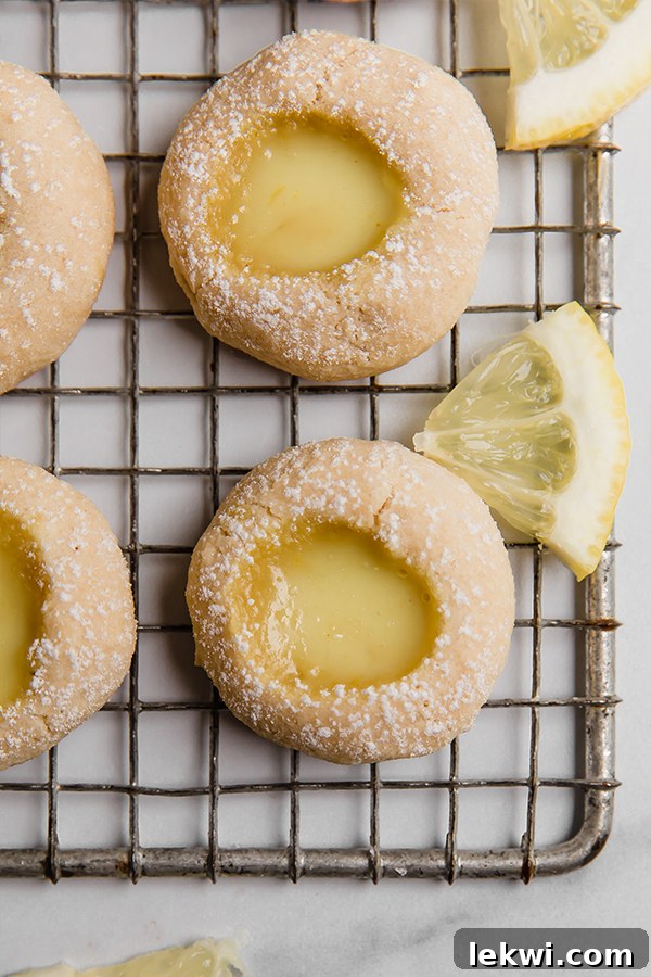Top-down view of freshly baked lemon bar thumbprint cookies cooling on a wire rack.