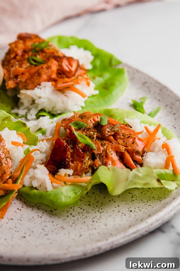 Two vibrant salmon lettuce wraps beautifully arranged on a white plate.